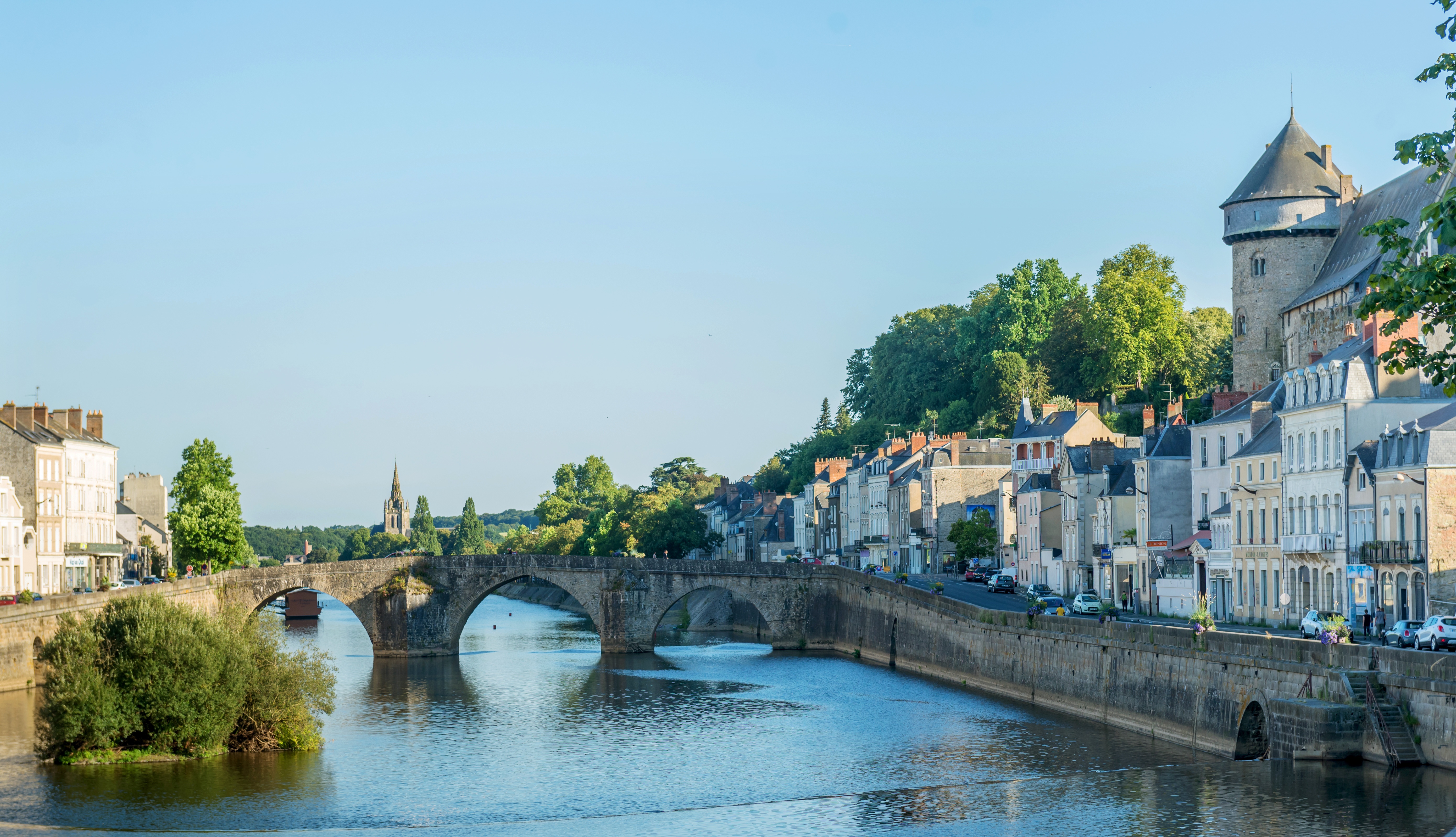 Photo d'un lieu emblématique de la ville de Laval, un pont au dessus d'un canal avec la ville historique autour.